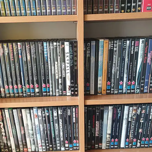 Ausschnitt eines Holzregals, das mit einer privaten Sammlung an DVDs befüllt ist.