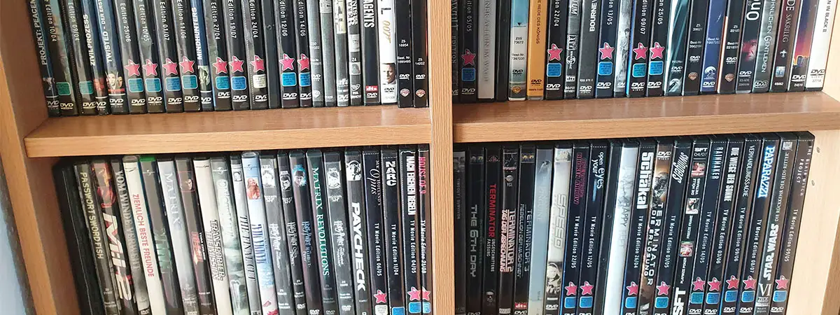Ausschnitt eines Holzregals, das mit einer privaten Sammlung an DVDs befüllt ist.