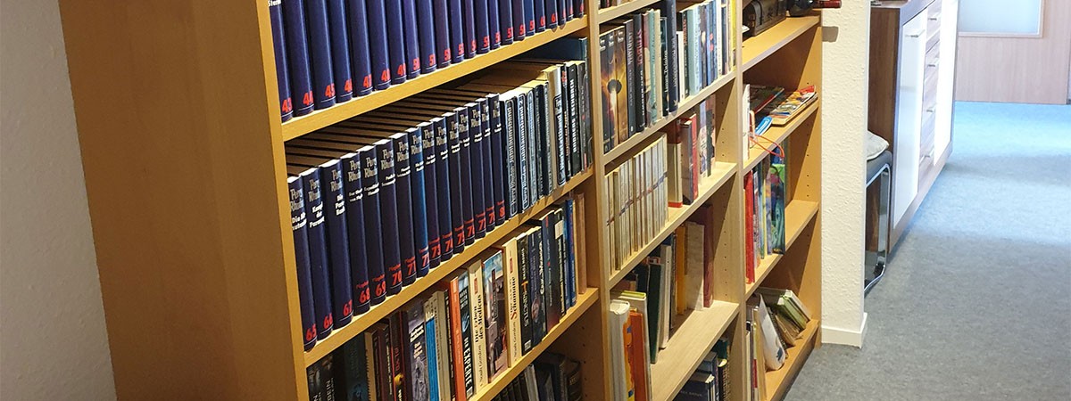 Holzregale im Flur sind befüllt mit einer privaten Bücher-Sammlung.