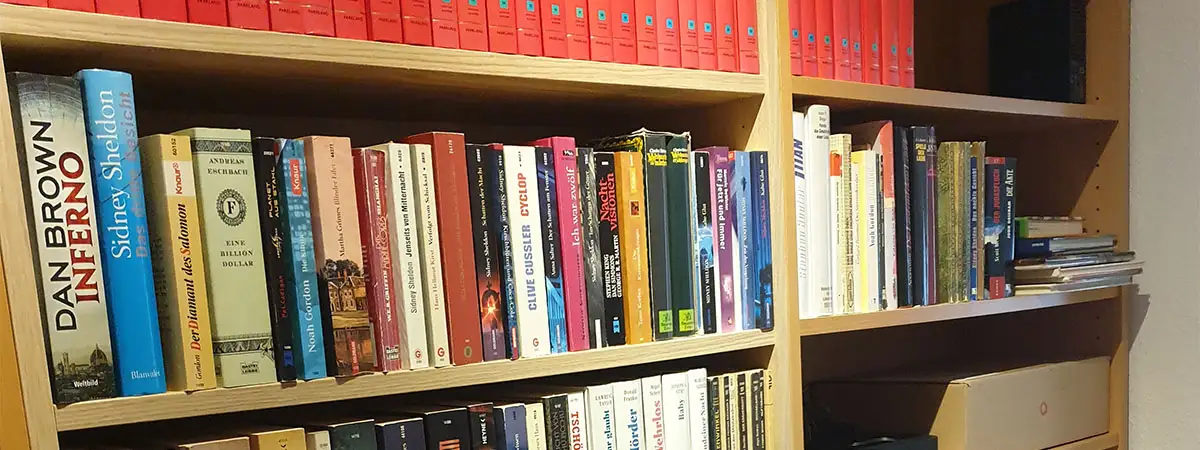 Holzregale sind befüllt mit einer privaten Bücher-Sammlung.