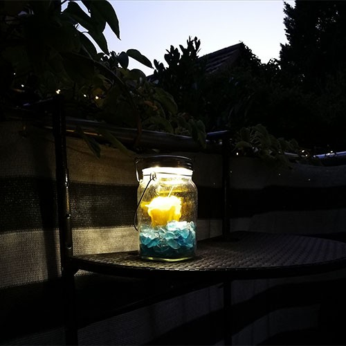 Kerze im Glas bei Dunkelheit auf einem halbrunden kleinen Tisch auf dem Balkon