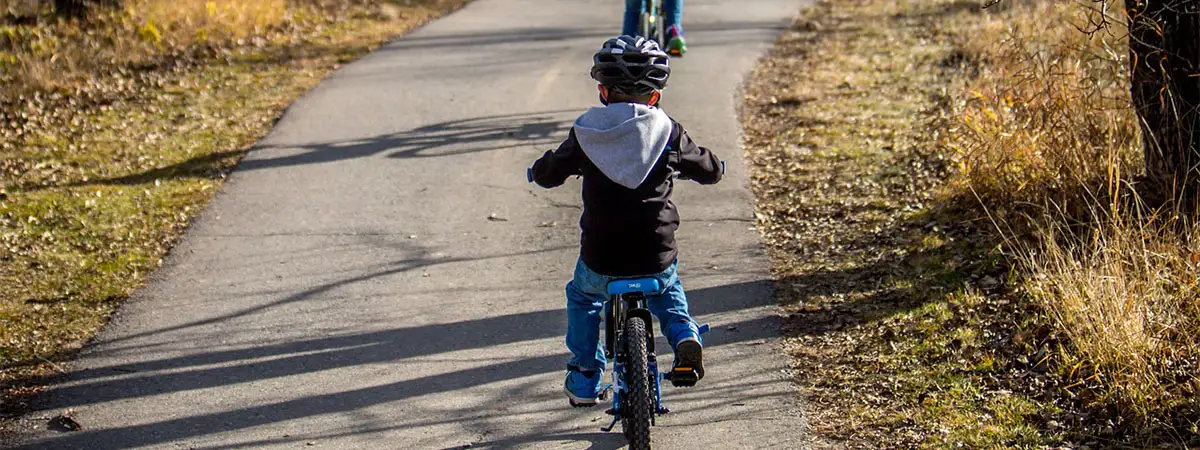 Eine Familie mit zwei Kindern fährt gemeinsam Fahrrad auf einem Waldweg.