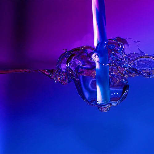 Ein lila eingefärbtes Bild, auf dem Ein Strohhalm zu sehen ist, der in eine Flüssigkeit getunkt wird.