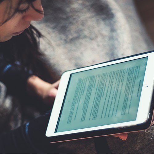 Eine Frau liest einen digitalen Text auf einem Tablet.