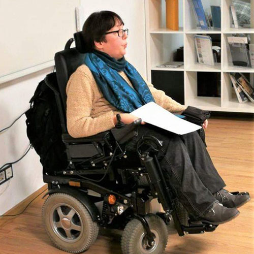 SMA-Patientin Camilla sitzt in ihrem Rollstuhl und hält einen Vortrag im beruflichen Kontext.