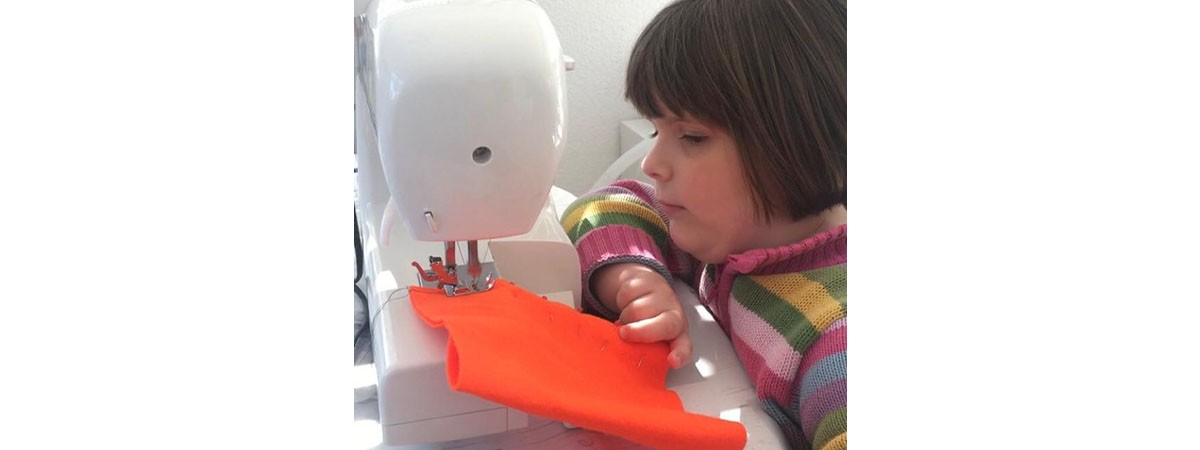 Die sechsjährige Patientin mit SMA Typ II geht einem ihrer Hobbies nach. Das Mädchen sitzt an einer Nähmaschine und näht.