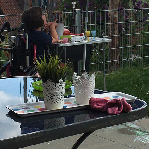 Die sechsjährige Patientin mit SMA Typ II geht ihrem Hobby nach. Das Mädchen sitzt draußen im Garten und spielt