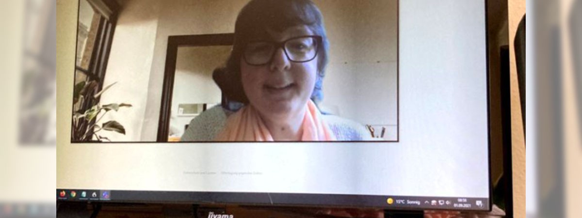 Eine Webcam zeichnet SMA-Patientin Camilla auf, sodass sie im Bildschirm eines Monitors auf einem Arbeits-Schreibtisch zu sehen ist.