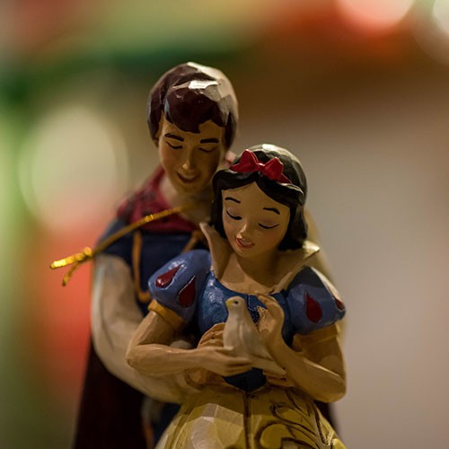 Zwei Holzfiguren sind zu sehen: Schneewittchen und ihr Märchenprinz, der sie umarmt.
