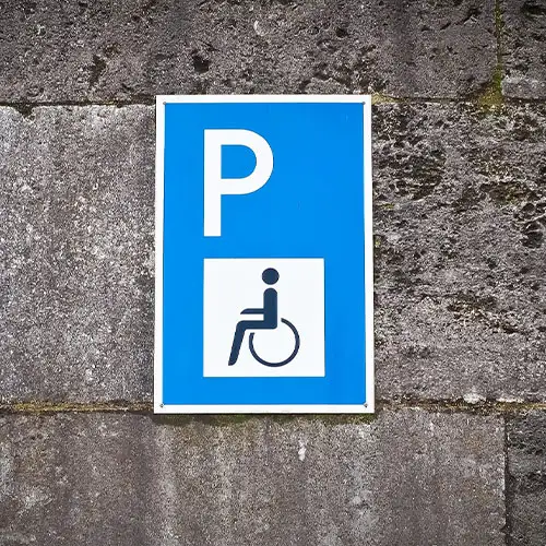 Ein Straßenschild mit einem Rollstuhlsymbol, das einen Parkplatz als Behindertenparkplatz kennzeichnet.