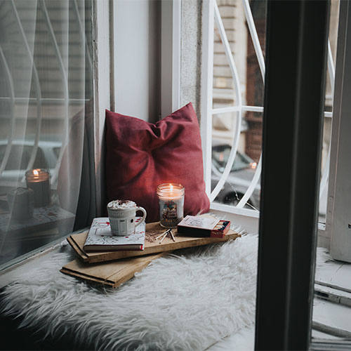 Auf einem braunen Ledersessel liegen ein weißes Kissen, eine Decke und eine weiße Kaffeetasse.