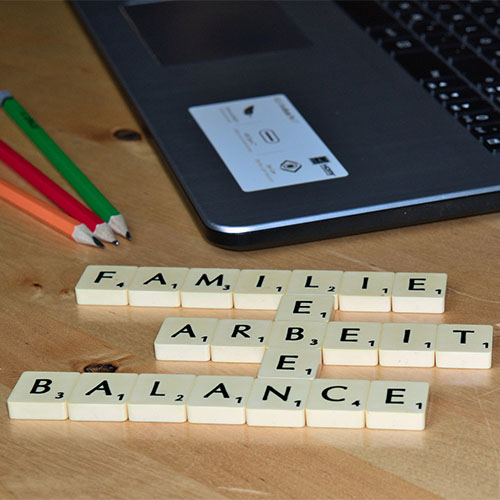 Mit Buchstabenplättchen stehen die Wörter Familie, Arbeit, Balance und Leben geschrieben. 