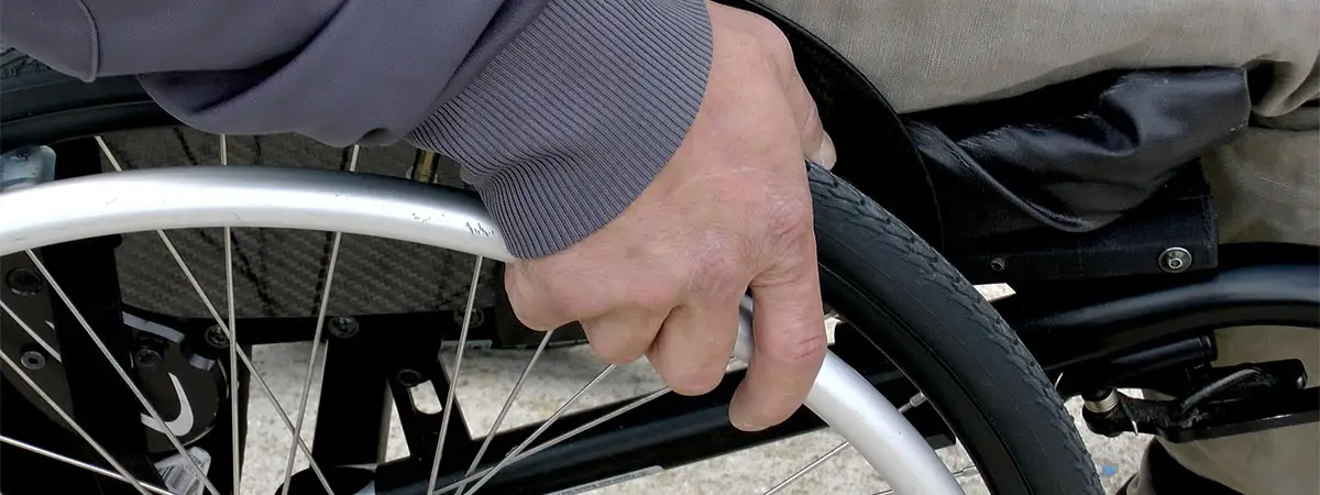 Ausschnitt eines manuellen Rollstuhls, der per Hand betrieben wird.