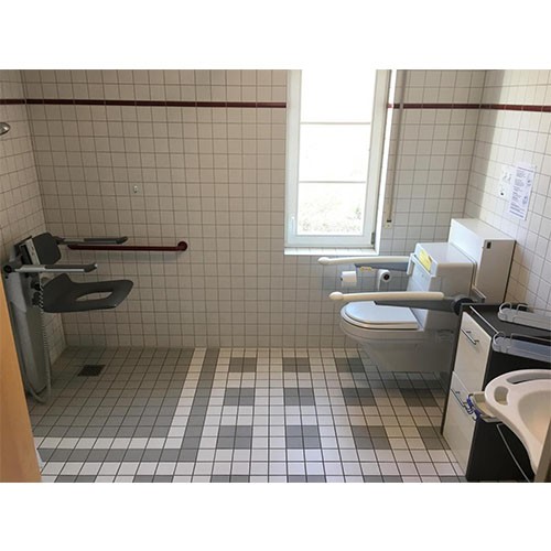 Barrierefreies Bad mit verstellbaren Sanitäranlagen: Einer ebenerdigen, höhenverstellbaren Dusche sowie behindertengerechten Toilette und Waschbecken.