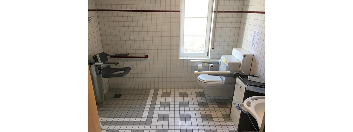 Barrierefreies Bad mit verstellbaren Sanitäranlagen: Einer ebenerdigen, höhenverstellbaren Dusche sowie behindertengerechten Toilette und Waschbecken.