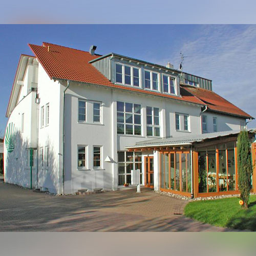 Ein Haus des Konzepts DGM-Probewohnen mit weißer Fassade und Wintergarten.  