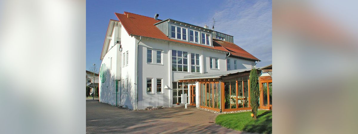 Ein Haus des Konzepts DGM-Probewohnen mit weißer Fassade und Wintergarten.  