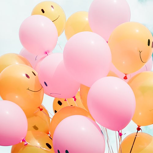 Orange und rosa Luftballons mit fröhlichen und traurigen Gesichtern.