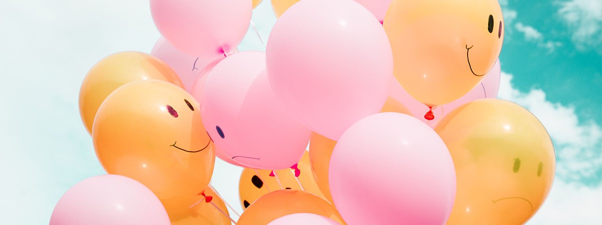 Orange und rosa Luftballons mit fröhlichen und traurigen Gesichtern.