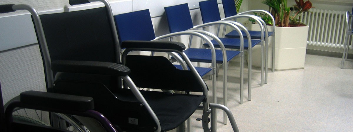 Warteraum einer Arztpraxis mit Stühlen und einem Rollstuhl