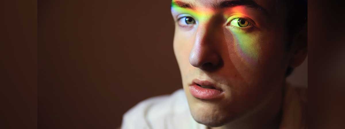 Ein Mann hat Lichtreflexe auf dem Gesicht, die einen Regenbogen formen. 