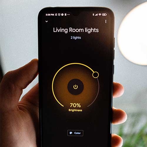 Ein Smartphone mit einer Smart-Home-App, die die Lichter der Wohnung steuert. Auf dem Display steht: Living Room lights, 2 lights, 70% Brightness, color.