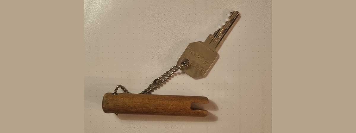 Ein Schlüssel für eine Haustüre hängt an einem Stück eingeschnitztem Holz.