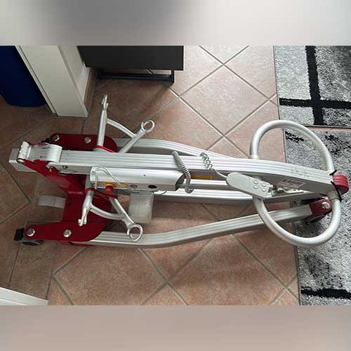 Ein mobiler Tragelifter zum Heben und Transportieren von Menschen mit körperlichen Einschränkungen ist zusammengeklappt und liegt auf dem Boden.
