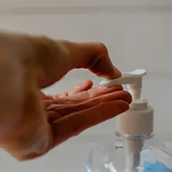 Eine Hand, die einen Hygienespender betätigt.