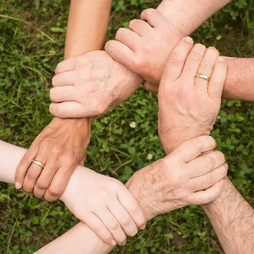 sechs Hände halten sich gegenseitig am Handgelenk und bilden einen Kreis