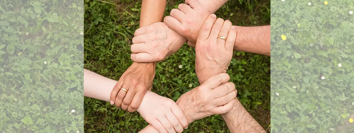 sechs Hände halten sich gegenseitig am Handgelenk und bilden einen Kreis