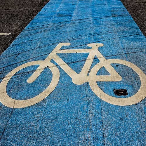 Ein Foto eines blau markierten Fahrradwegs mit einem weißen Fahrradsymbol auf glattem Asphalt. 