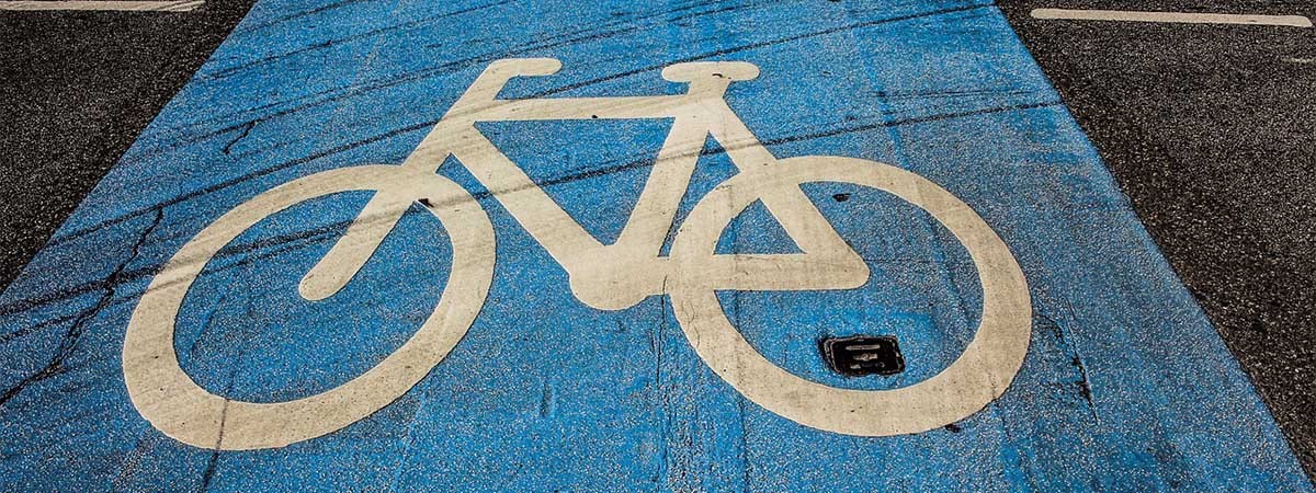 Ein Foto eines blau markierten Fahrradwegs mit einem weißen Fahrradsymbol auf glattem Asphalt. 