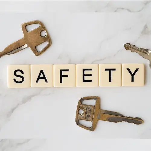 Ein Bild mit Scrabble-Buchstaben, die das Wort „SAFETY“ bilden. Darum befinden sich drei Schlüssel, die auf einem Marmortisch liegen. 