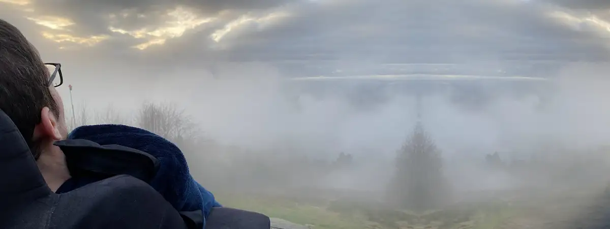 Ein Bild von Roberto, der im Rollstuhl in eine neblige Landschaft mit dunklen Wolken am Himmel blickt.