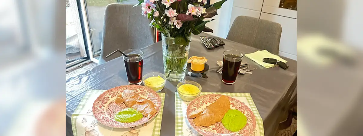 Gedeckter Tisch mit Blumen, angerichtetem Essen und Getränk