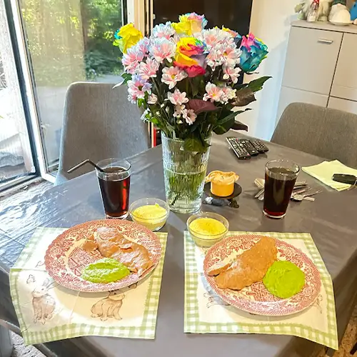 Gedeckter Tisch mit Blumen, angerichtetem Essen und Getränk