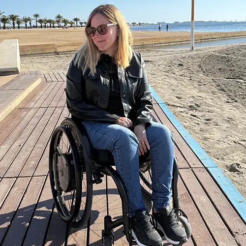 Ein Foto von Svenja im Rollstuhl auf einem Holzsteg am Strand.