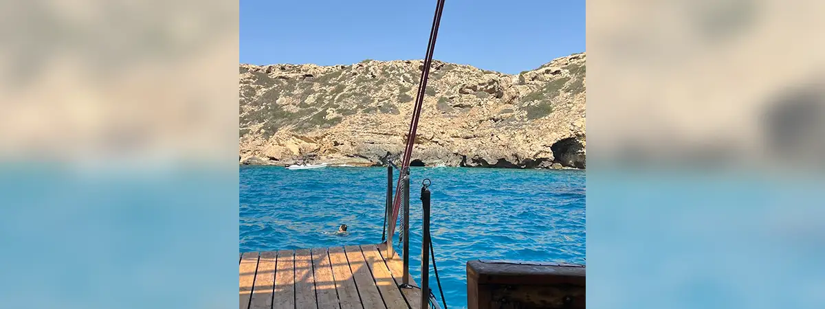 Ein Foto eines Steges mit blauem Wasser und einer felsigen Küste im Hintergrund.