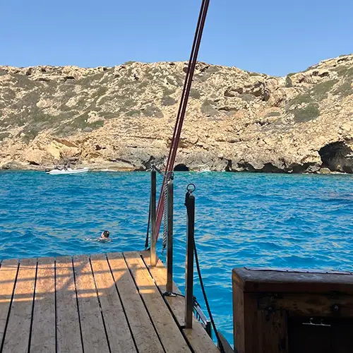 Ein Foto eines Steges mit blauem Wasser und einer felsigen Küste im Hintergrund.