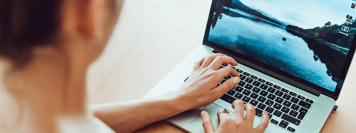 Ein Foto einer Frau, die an ihrem Schreibtisch sitzt und an ihrem Laptop arbeitet.