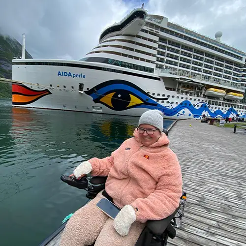 Alina, die sich am Wasser auf einem Steg befindet – hinter ihr ist das AIDA Kreuzfahrtschiff.