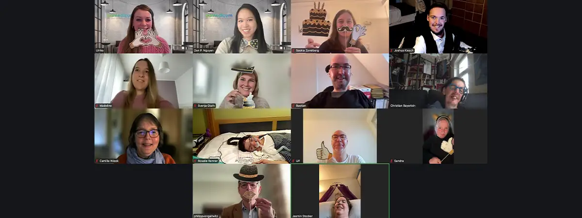Foto des virtuellen Meetings: Redaktionsteam und admedicum halten lächelnd Fotorequisiten in die Kamera.