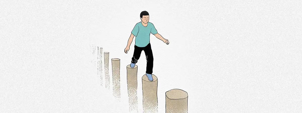 Ein Mann, der über Holzpfosten balanciert – Symbol für das Überwinden von Herausforderungen.