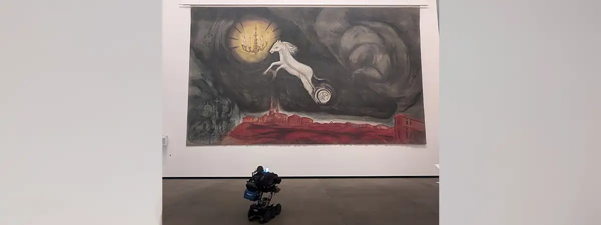 Christian liegt in seinem eRollstuhl und betrachtet eine große Kunstinstallation im Museum.  