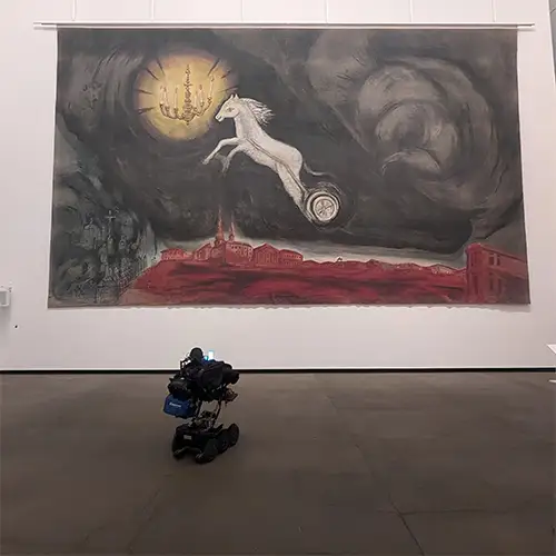 Christian liegt in seinem eRollstuhl und betrachtet eine große Kunstinstallation im Museum.  
