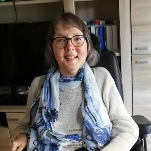 Ein Porträtfoto von Camilla im Rollstuhl – sie lächelt offen und blickt in die Kamera.