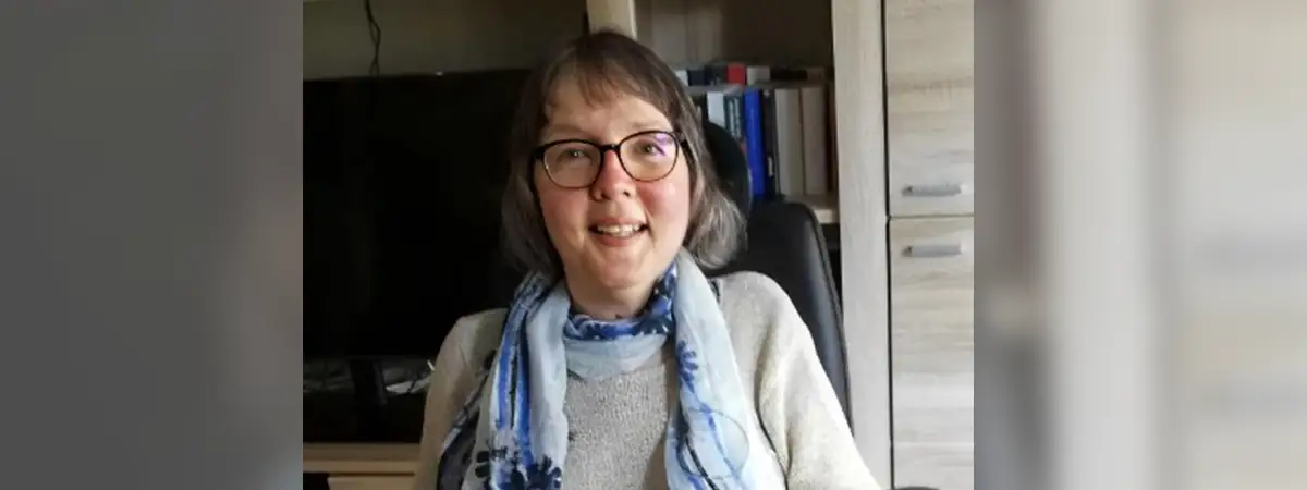 Ein Porträtfoto von Camilla im Rollstuhl – sie lächelt offen und blickt in die Kamera.