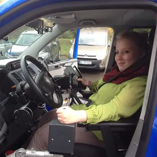 Ein Foto von Sandra, die am Steuer ihres umgebauten Autos mit speziellen Fahrzeuganpassungen sitzt.