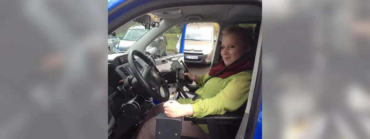 Ein Foto von Sandra, die am Steuer ihres umgebauten Autos mit speziellen Fahrzeuganpassungen sitzt.